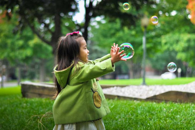 young girl about to burst a bubble whilst playing outside
