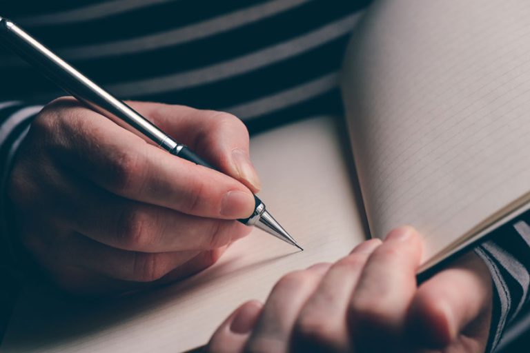 close up of person writing in a book