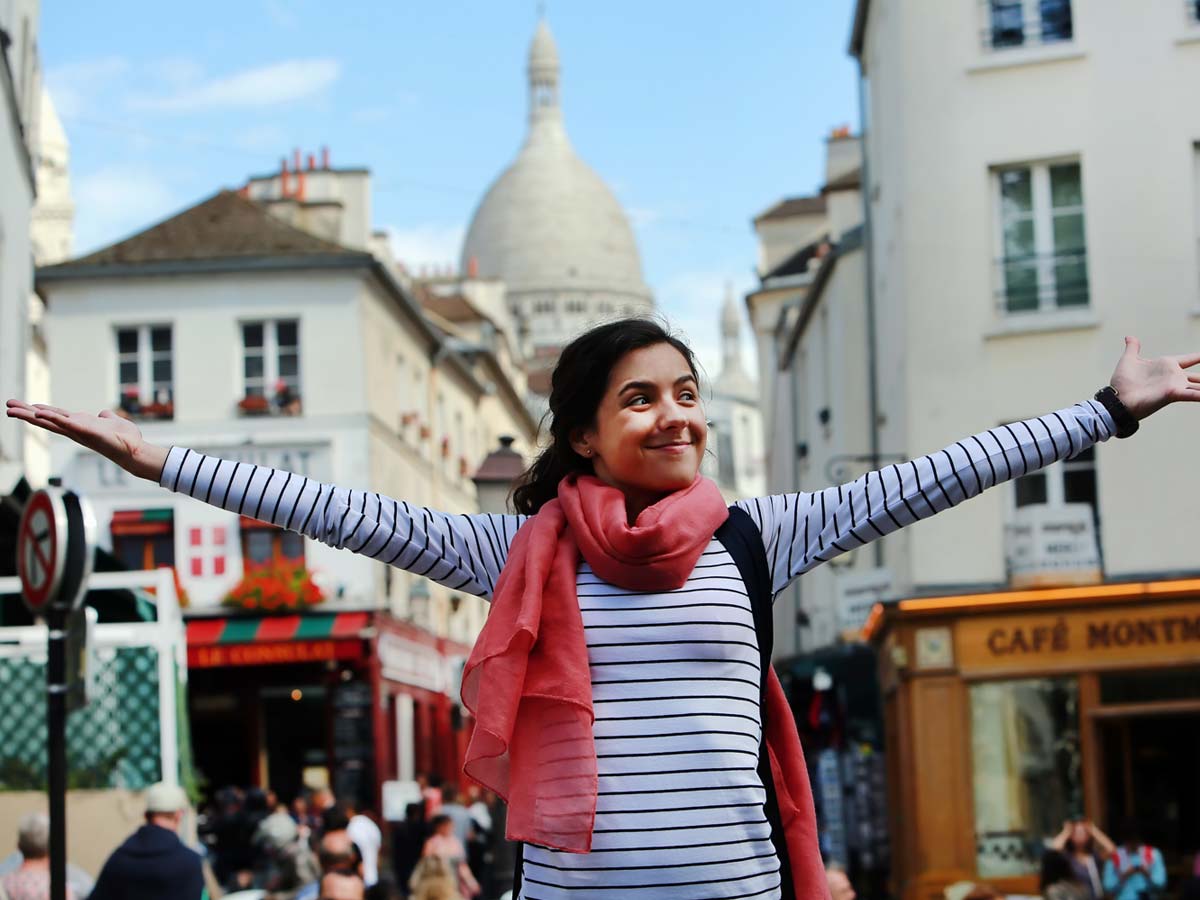young smiling woman with arms outstretched in Paris