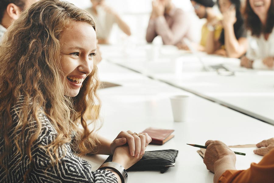 Young woman smiling, sat at meeting table