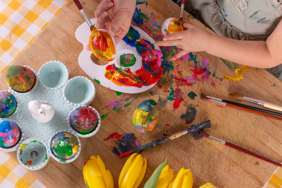 Child and adult painting easter eggs