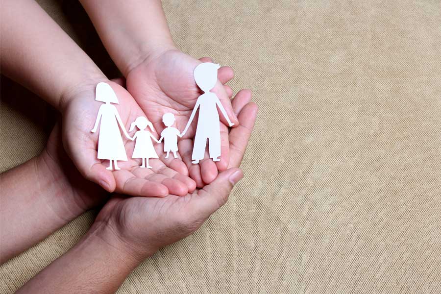 hands of adult and child holding paper cut out of family unit