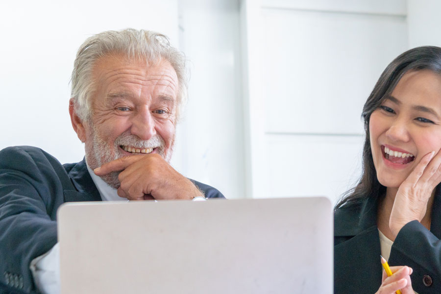 elder gentleman and younger lady looking at a computer