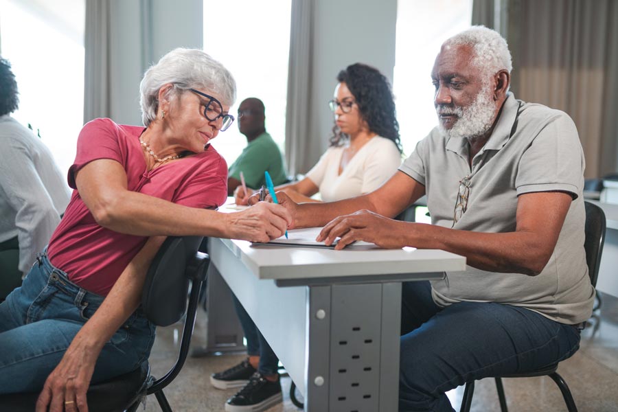 male and female adult learners helping each other in classroom